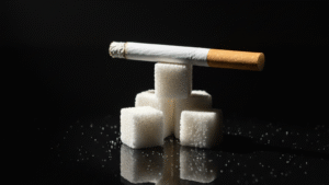 Cigarette balanced on white sugar cubes showing hidden sugar content in tobacco products and smoking health risks