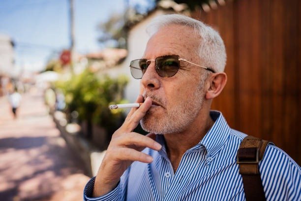 Mature man smoking a cigarette on the sidewalk