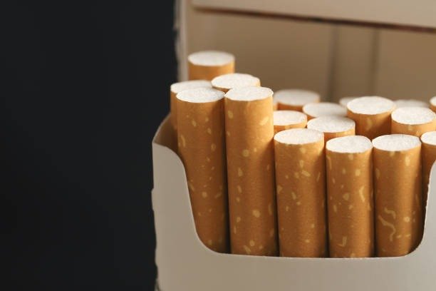 Peeling off a cigarette pack on a white wooden background
