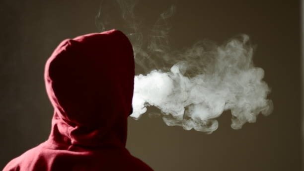 Young male vaping and exhaling thick vapor